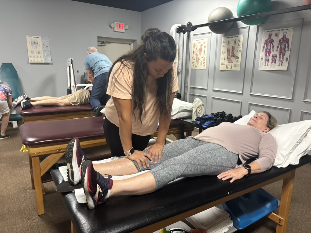 Yaya stretching a patient's leg during therapy